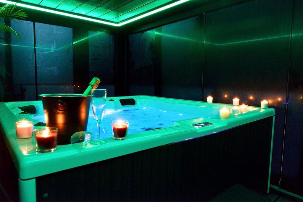 Grand jacuzzi carré dans une suite spacieuse avec décoration jungle chic et éclairage d'ambiance à Liège.